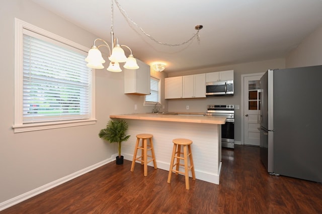 102 Moore Ave, Portland, TN 37148 - kitchen featuring dark wood-style flooring, appliances with stainless steel finishes, an inviting chandelier, and a peninsula