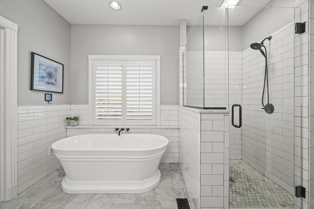 6437 Arno Rd, College Grove, TN 37046 - bathroom featuring a stall shower, a wainscoted wall, a freestanding bath, tile walls, and marble finish floors