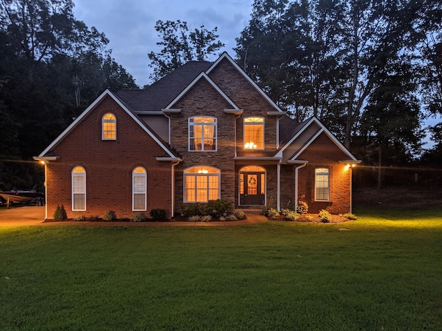 view of front of property featuring brick siding, a front yard, and stone siding