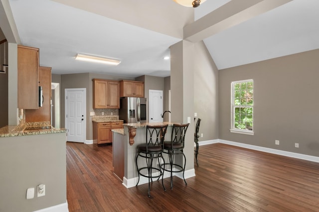 990 Iron Hill Rd, Burns, TN 37029 - kitchen with stainless steel refrigerator with ice dispenser, a peninsula, light stone counters, dark wood-style flooring, and a kitchen breakfast bar