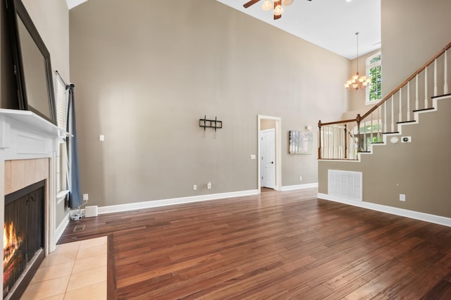 990 Iron Hill Rd, Burns, TN 37029 - unfurnished living room featuring high vaulted ceiling, hardwood / wood-style flooring, ceiling fan, stairway, and a tiled fireplace