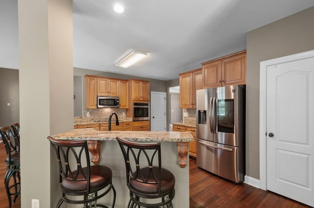 990 Iron Hill Rd, Burns, TN 37029 - kitchen featuring stainless steel appliances, dark wood-style flooring, tasteful backsplash, a breakfast bar, and light stone countertops