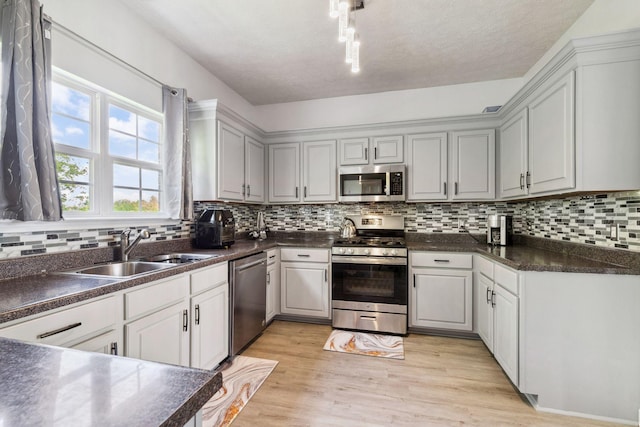 5512 Oak Chase Dr, Antioch, TN 37013 - kitchen with dark countertops, light wood-style floors, tasteful backsplash, a sink, and stainless steel appliances