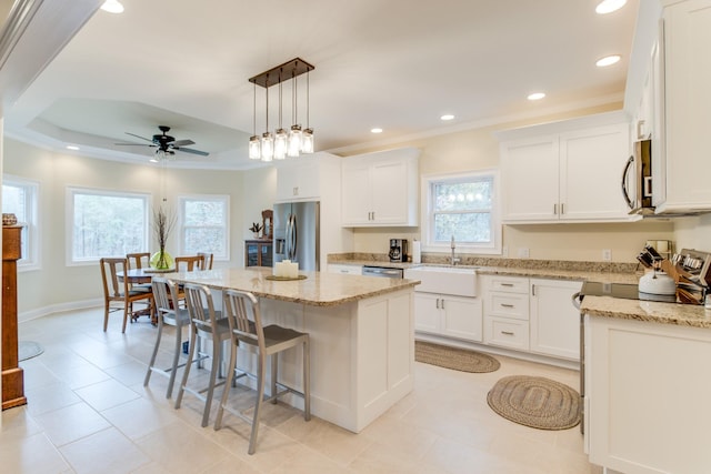 kitchen featuring plenty of natural light, a ceiling fan, a center island, a sink, and stainless steel appliances