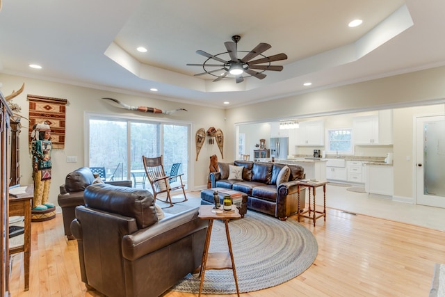 living room with recessed lighting, a raised ceiling, ceiling fan, and a wealth of natural light