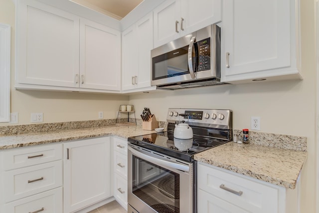 kitchen featuring white cabinets, appliances with stainless steel finishes, and light stone counters
