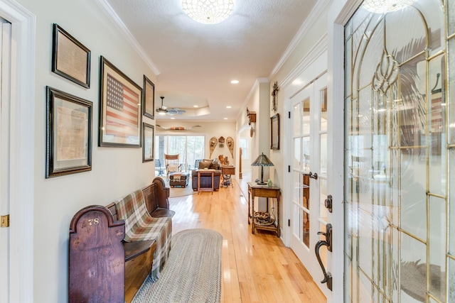hallway with crown molding, french doors, and light wood-style flooring