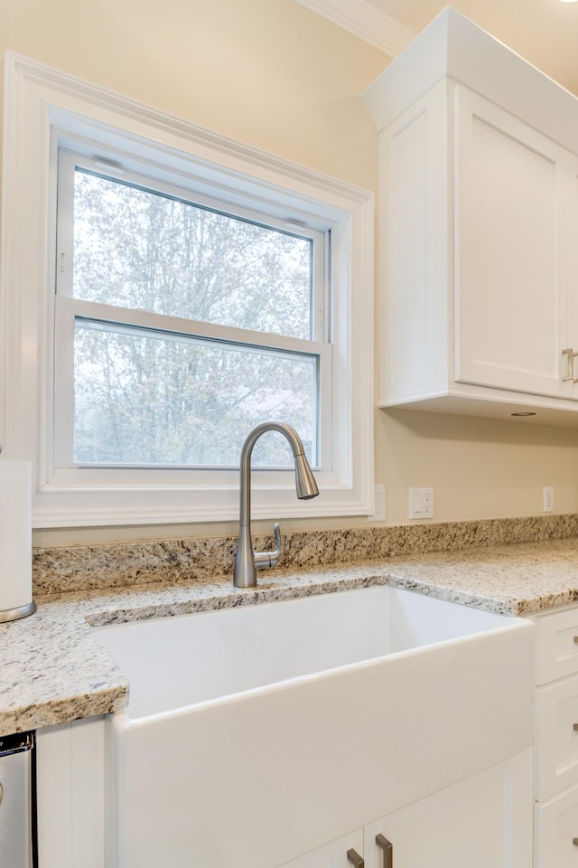 room details with white cabinetry, light stone counters, and a sink