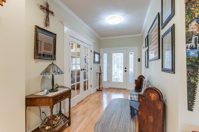 foyer featuring light wood-style floors, ornamental molding, and french doors