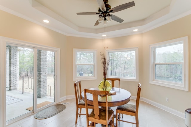dining area featuring light tile patterned flooring, ceiling fan, a healthy amount of sunlight, and a raised ceiling