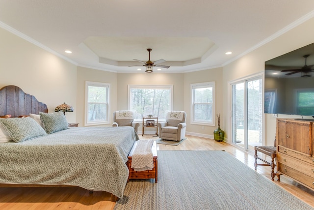 bedroom with multiple windows, a tray ceiling, and light wood finished floors