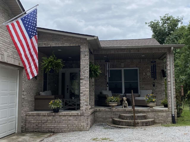 property entrance featuring a shingled roof, a porch, and brick siding