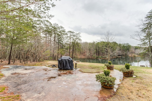 view of yard with a patio, a water view, and a wooded view