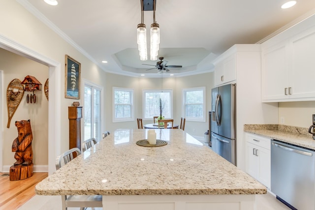 kitchen featuring ceiling fan, a center island, white cabinetry, a tray ceiling, and appliances with stainless steel finishes