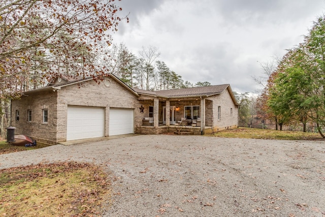 ranch-style home with covered porch, an attached garage, driveway, and brick siding