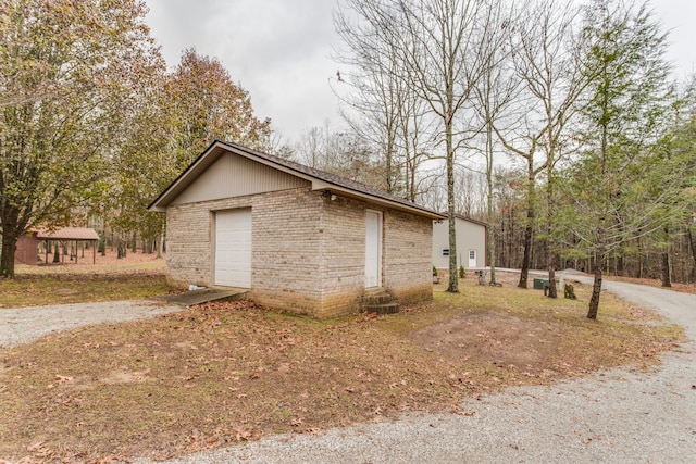 view of property exterior featuring an outbuilding, driveway, and brick siding