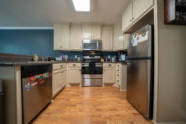 215 Desperado Ave, Pulaski, TN 38478 - kitchen with dark countertops, cream cabinets, a sink, light wood finished floors, and stainless steel appliances