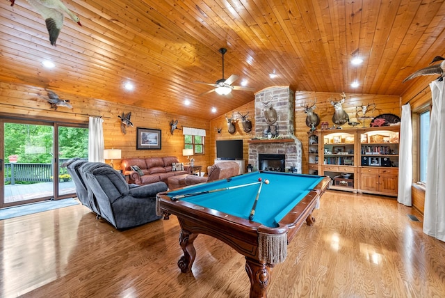 game room featuring vaulted ceiling, wood ceiling, plenty of natural light, a stone fireplace, and wood finished floors