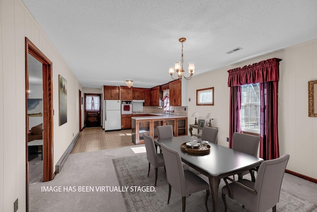dining area featuring a textured ceiling, visible vents, baseboards, a notable chandelier, and light carpet