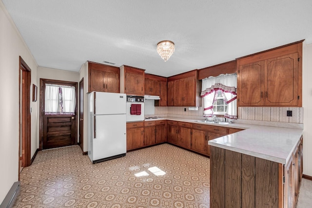 kitchen with light countertops, a peninsula, a healthy amount of sunlight, and white appliances