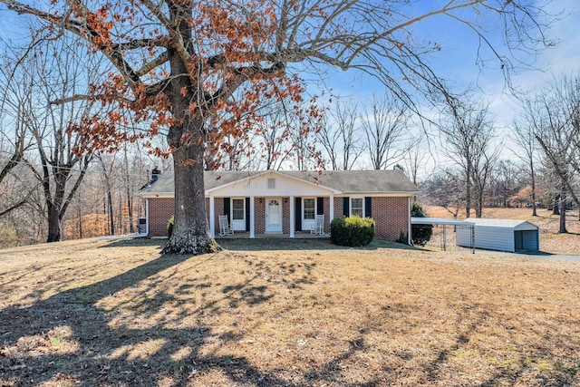 view of front facade with covered porch, an outdoor structure, a front yard, and brick siding