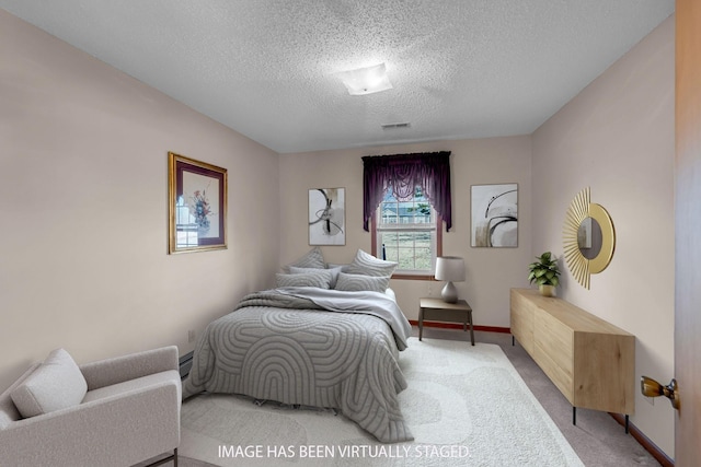 carpeted bedroom featuring a baseboard heating unit, a textured ceiling, visible vents, and baseboards