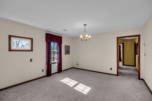 unfurnished room featuring a notable chandelier, light colored carpet, a textured ceiling, baseboards, and visible vents