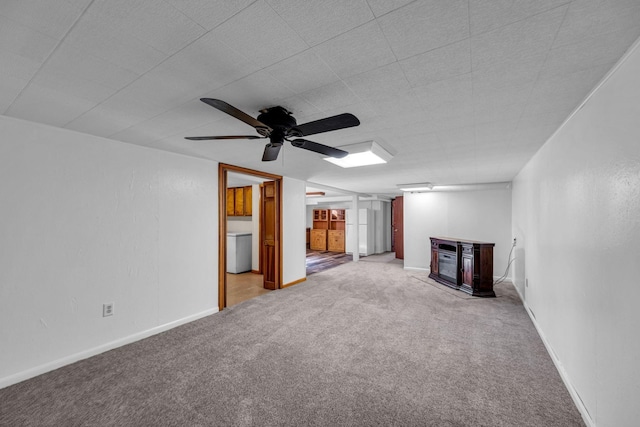 unfurnished living room featuring a ceiling fan, baseboards, a glass covered fireplace, and light carpet