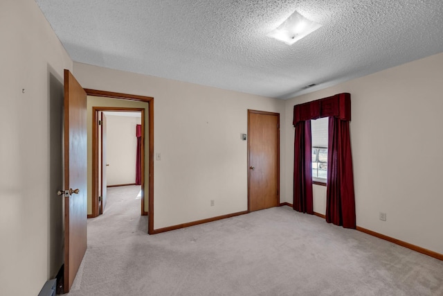 empty room with baseboards, light carpet, and a textured ceiling