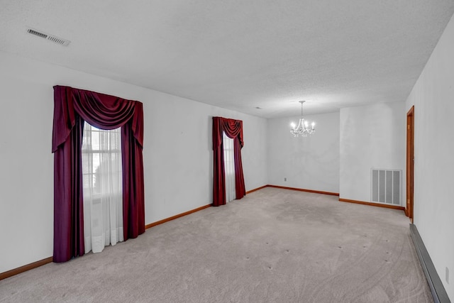 spare room featuring visible vents, carpet flooring, a baseboard heating unit, and a chandelier
