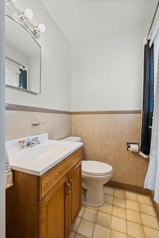 bathroom featuring vanity, toilet, tile walls, and a wainscoted wall