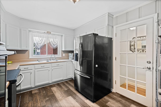 kitchen featuring white cabinets, black fridge, and a sink