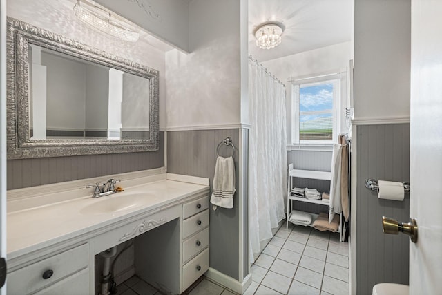 bathroom with a wainscoted wall, tile patterned flooring, vanity, and curtained shower