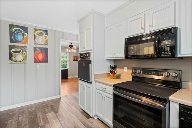 kitchen with crown molding, light countertops, white cabinetry, light wood-style flooring, and black appliances
