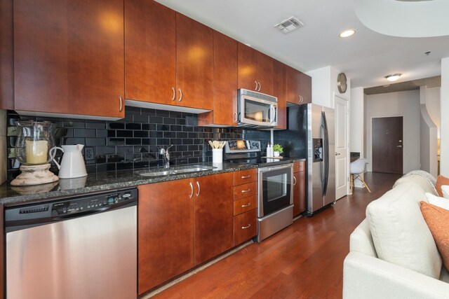 kitchen featuring appliances with stainless steel finishes, a sink, dark wood finished floors, backsplash, and visible vents