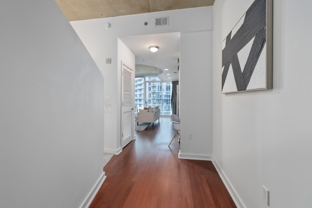 corridor with baseboards, visible vents, floor to ceiling windows, and wood finished floors