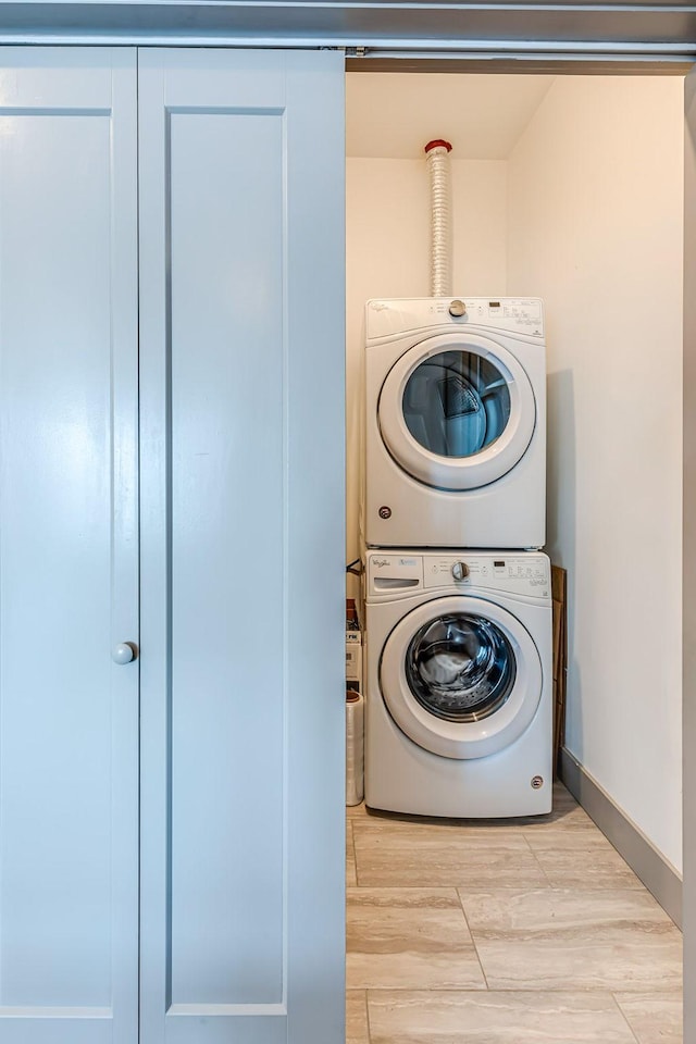 laundry area with light wood finished floors, laundry area, and stacked washer and dryer