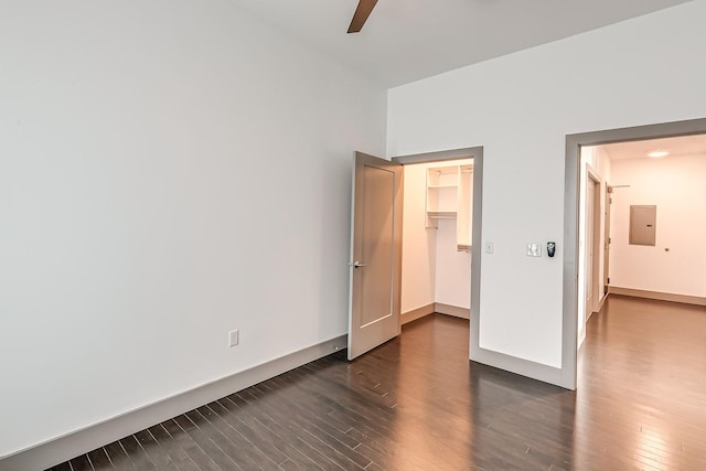 unfurnished bedroom featuring dark wood-style flooring, electric panel, a ceiling fan, a spacious closet, and a closet
