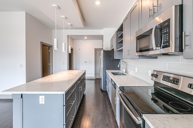 kitchen with a sink, gray cabinets, appliances with stainless steel finishes, and tasteful backsplash