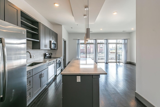 kitchen featuring appliances with stainless steel finishes, a center island, open shelves, a sink, and gray cabinetry