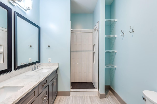 full bathroom featuring double vanity, a sink, a tile shower, and toilet