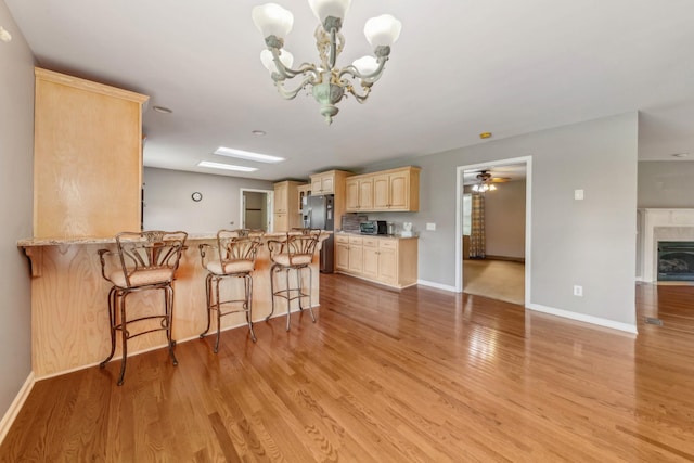 447 Canaan Rd, Columbia, TN 38401 - kitchen with a peninsula, light brown cabinets, light wood-style floors, baseboards, and a kitchen breakfast bar