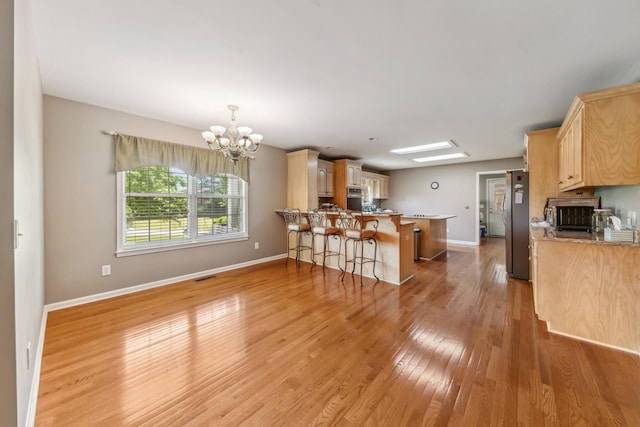 447 Canaan Rd, Columbia, TN 38401 - kitchen with an inviting chandelier, freestanding refrigerator, a peninsula, baseboards, and light wood-type flooring