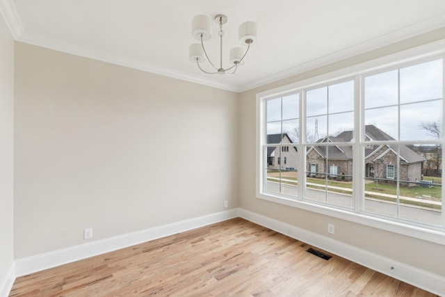 empty room with baseboards, ornamental molding, light wood-type flooring, and an inviting chandelier