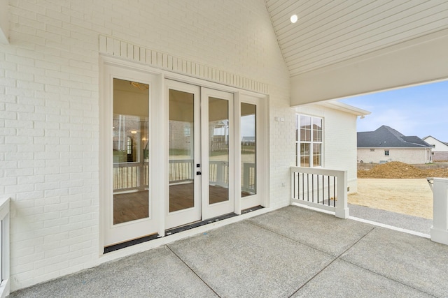 entrance to property featuring brick siding, french doors, and a patio area
