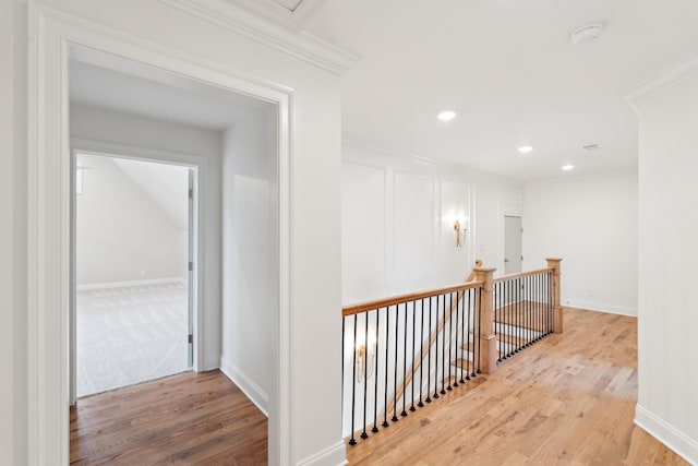 corridor with crown molding, wood finished floors, and an upstairs landing