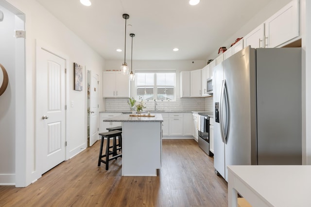 301 Harper Lndg Unit 301, Chapel Hill, TN 37034 - kitchen with stainless steel appliances, a kitchen island, a breakfast bar area, white cabinets, and decorative backsplash
