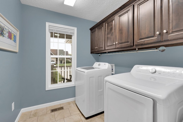 165 Daffodil Dr, Tullahoma, TN 37388 - laundry room featuring cabinet space, washer and dryer, baseboards, a textured ceiling, and light tile patterned floors
