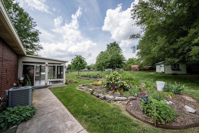 view of yard featuring fence, central AC unit, an outdoor structure, and a sunroom