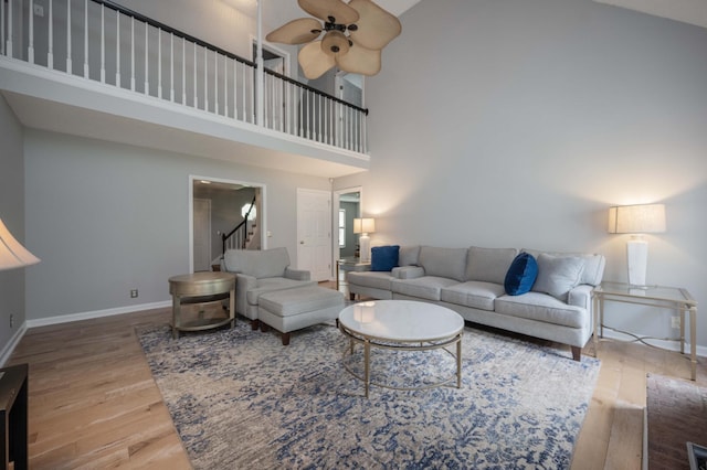 living room featuring stairs, ceiling fan, baseboards, and wood finished floors